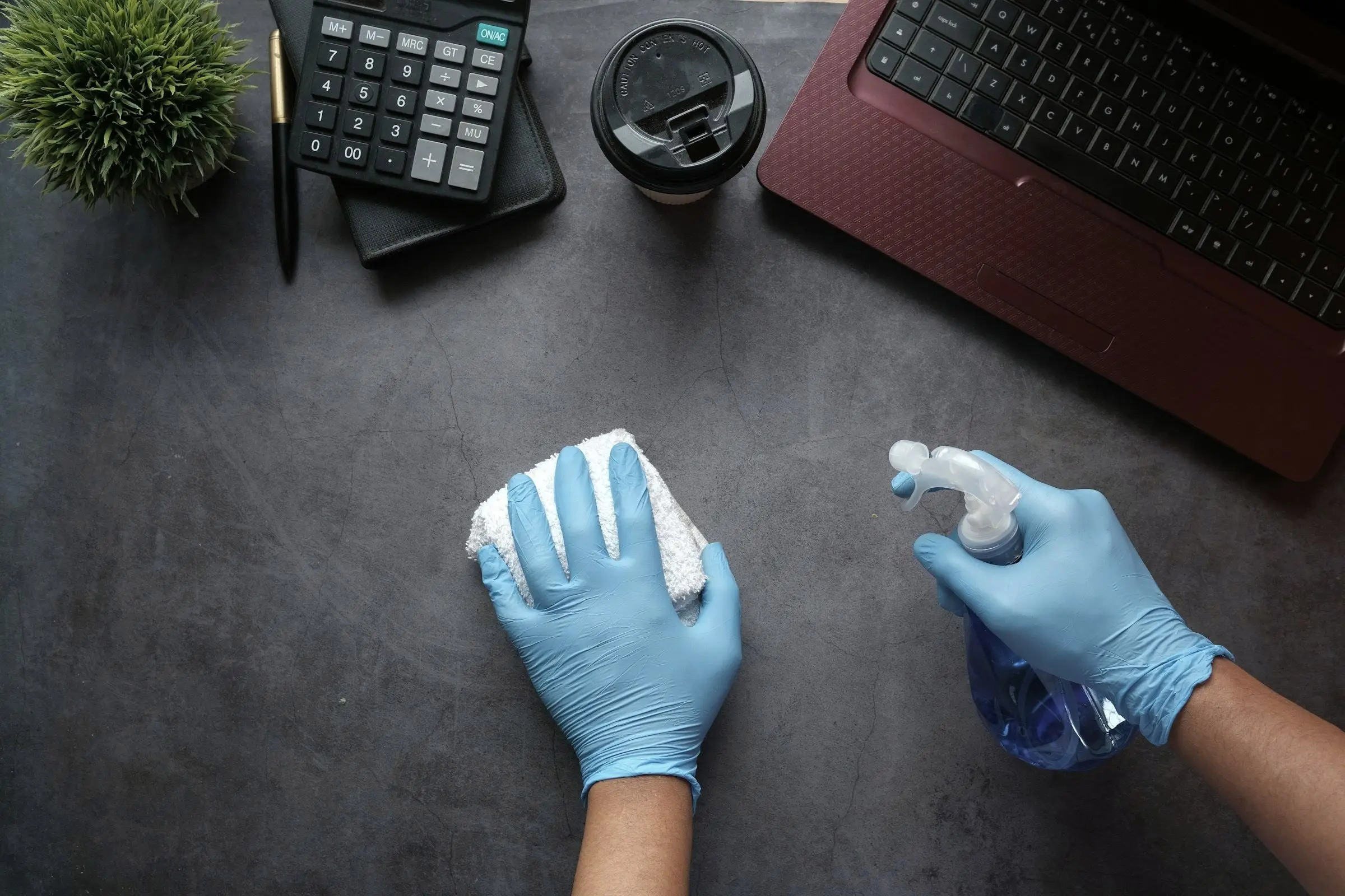 Mains gantées nettoyant un bureau